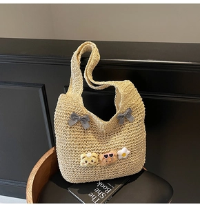 Détail d'un sac cabas en paille beige avec nœuds vichy et décors d'animaux en peluche