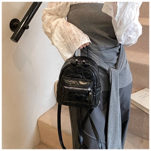 Close-up of women's black mini backpack with elegant heart-shaped quilted pattern