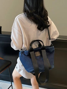 Grand sac cabas en denim bleu foncé avec anses noires et logo D porté par un mannequin