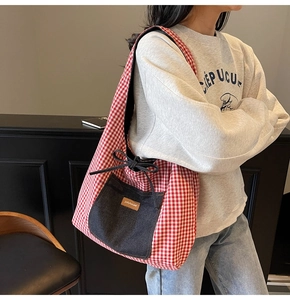 Detail of red checkered canvas tote bag with denim pocket and drawstring bow accent