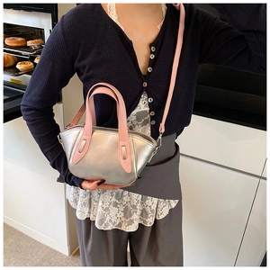 Fashionable silver metallic bucket bag with pink straps worn by a model in a cozy kitchen
