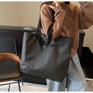 Close-up of black nylon tote bag showing durable fabric and vertical letter printing