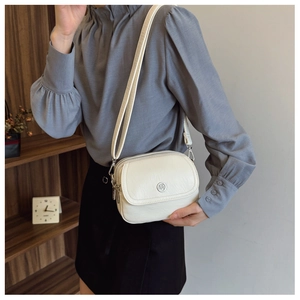 Detail of off-white multi-layer crossbody bag with three metal zippers and pebbled texture
