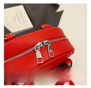 Détail du sac polochon en cuir grainé rouge avec double fermeture éclair argentée