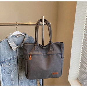Close-up of durable dark grey canvas tote bag with brown leather brand label detail
