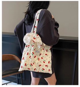 Close-up of white canvas tote bag with red cherry print and Magic pocket patch detail