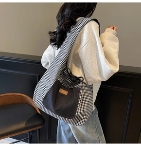 Detail of checkered tote bag with denim pocket and drawstring closure on a shoulder model