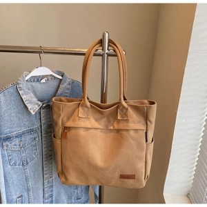 Close-up of khaki canvas tote bag showing front zipper pocket and Kerbag leather logo