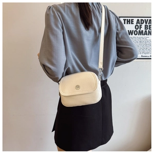 Detailed back view of model wearing cream crossbody bag with pebble leather texture