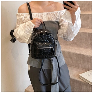 Close-up of black mini backpack with elegant heart-shaped quilting and silver zippers