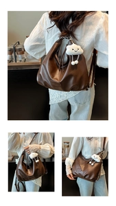 Gros plan du sac hobo plissé vintage avec un charme de nuage en peluche marron foncé