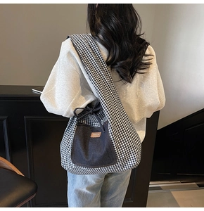 Detail of gingham tote bag with denim pocket showing textile texture and leather logo tag