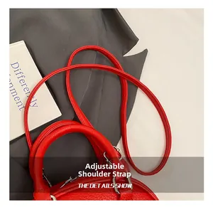 Détail macro du sac en cuir rouge avec bandoulière réglable et ferrures argentées
