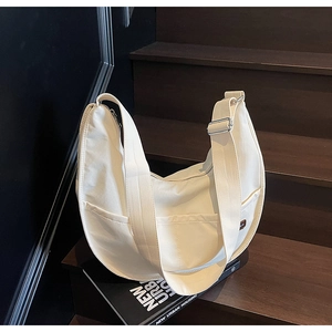 Detail view of cream canvas crescent bag on stairs with zipper and side pocket