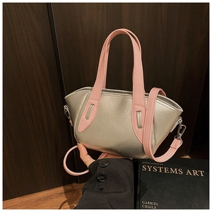 Close-up of silver bucket bag with pink straps and metallic logo on dark wood background