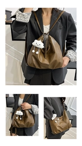 Détail du sac hobo en cuir souple marron avec un pendentif en peluche nuage blanc