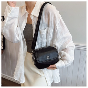 Detail of black pebbled leather saddle bag with silver logo and wide shoulder strap