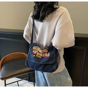 Detailed embroidery on blue denim messenger bag with vintage American style letters