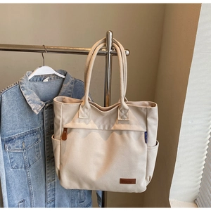 Close-up of cream canvas tote bag showing the KFRBAG leather logo and fabric texture