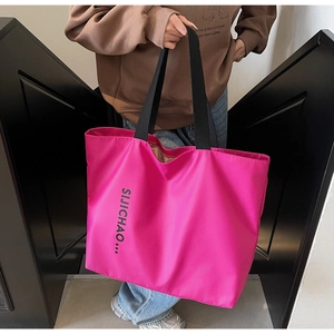 Detail of hot pink canvas tote bag with black straps and contrast letter printing
