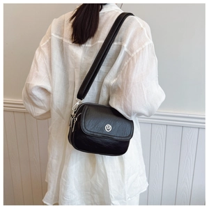 Close-up of black multi-zip crossbody bag with pebbled leather texture and metal logo