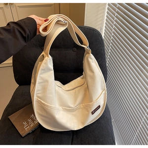 Detail view of the beige nylon tote bag with adjustable strap and brand leather patch