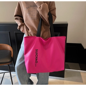 Close-up of fuchsia large tote bag with black letter print and durable nylon texture