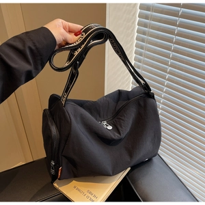 Detail of black nylon Boston crossbody bag with wide jacquard strap and orange side label