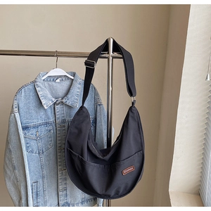 Close-up of black nylon crescent crossbody bag with adjustable strap and leather brand label