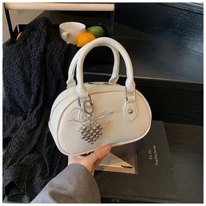 Détail d'un sac à main blanc motif litchi avec pendentif coeur en métal argenté brillant
