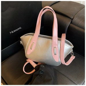 Detail of silver metallic textured crossbody bag with pink contrast handles and silver buckle