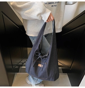 Detail of blue denim tote bag featuring a bow drawstring and black white checkered lining