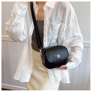Close-up of stylish black leather crossbody bag with three zip layers and silver logo buckle