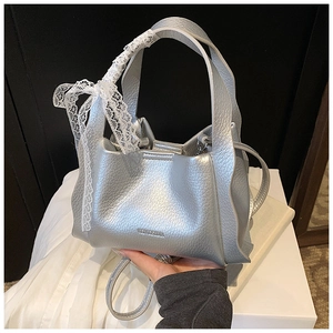 Detail of silver handbag featuring a lace bow, wavy side pleats and litchi grain texture