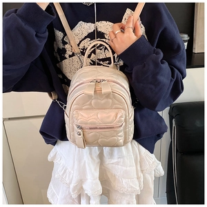 Detail of heart-quilted pattern and pearl luster finish on a cream mini backpack