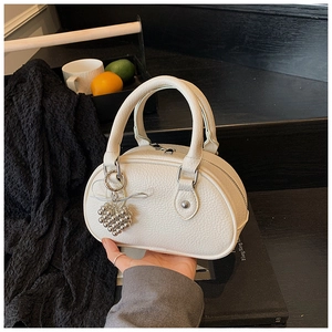 Détail du sac à main en cuir beige grainé avec pendentif en forme de cœur en perles argentées