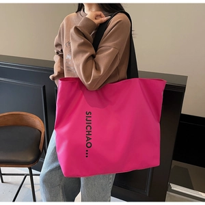 Detail of a large rose red tote bag with black letter printing for daily casual use