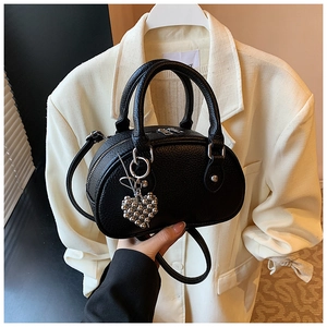 Détail du sac polochon noir en cuir grainé avec breloque cœur et double fermeture éclair