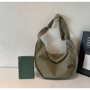 Close-up of olive green nylon tote bag featuring front pockets and adjustable strap
