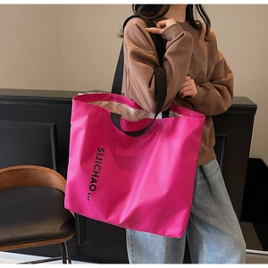 Detail of hot pink tote bag with black straps and letter print for casual style