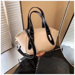 Close-up of cream white boat-shaped bucket bag with black handles and adjustable strap