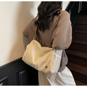 Detail of beige wrinkled nylon crossbody bag with side metal zipper and logo on a model