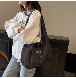 Detail of blue denim tote bag featuring brown leather logo and checkered lining texture