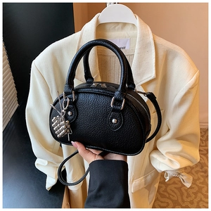 Détail du sac Boston en cuir grainé noir avec zips argentés et accessoire charm baie