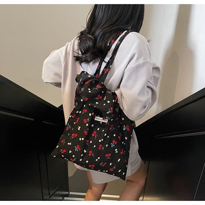 Detail of black canvas tote bag featuring red cherry prints and Magic Pocket label