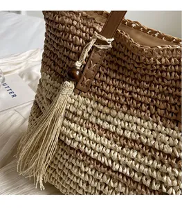 Detail of woven tote bag featuring brown leather handle and wooden bead tassel ornament
