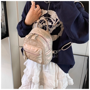 Detail of heart quilted mini backpack in pearlescent cream worn by a female model