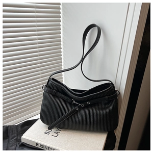 Detail view of black pleated leather shoulder bag with metallic eyelet buckle strap
