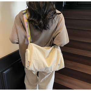 Detail of beige nylon crossbody bag featuring a wide jacquard logo shoulder strap