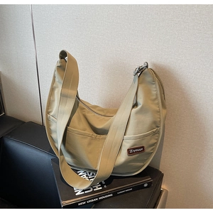 Close-up of olive green nylon hobo bag with side pockets on a leather sofa